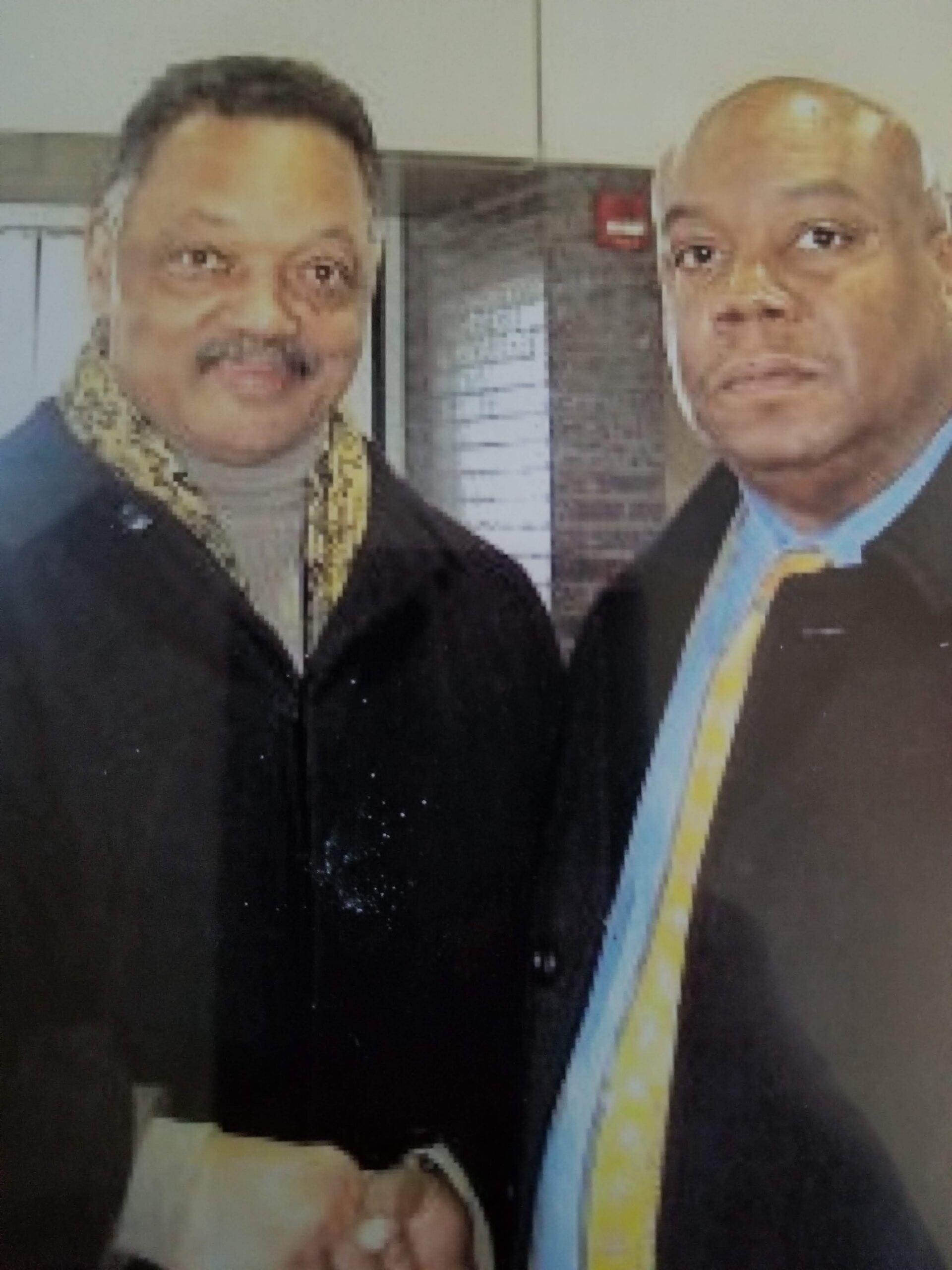 Two men standing together, wearing formal coats.