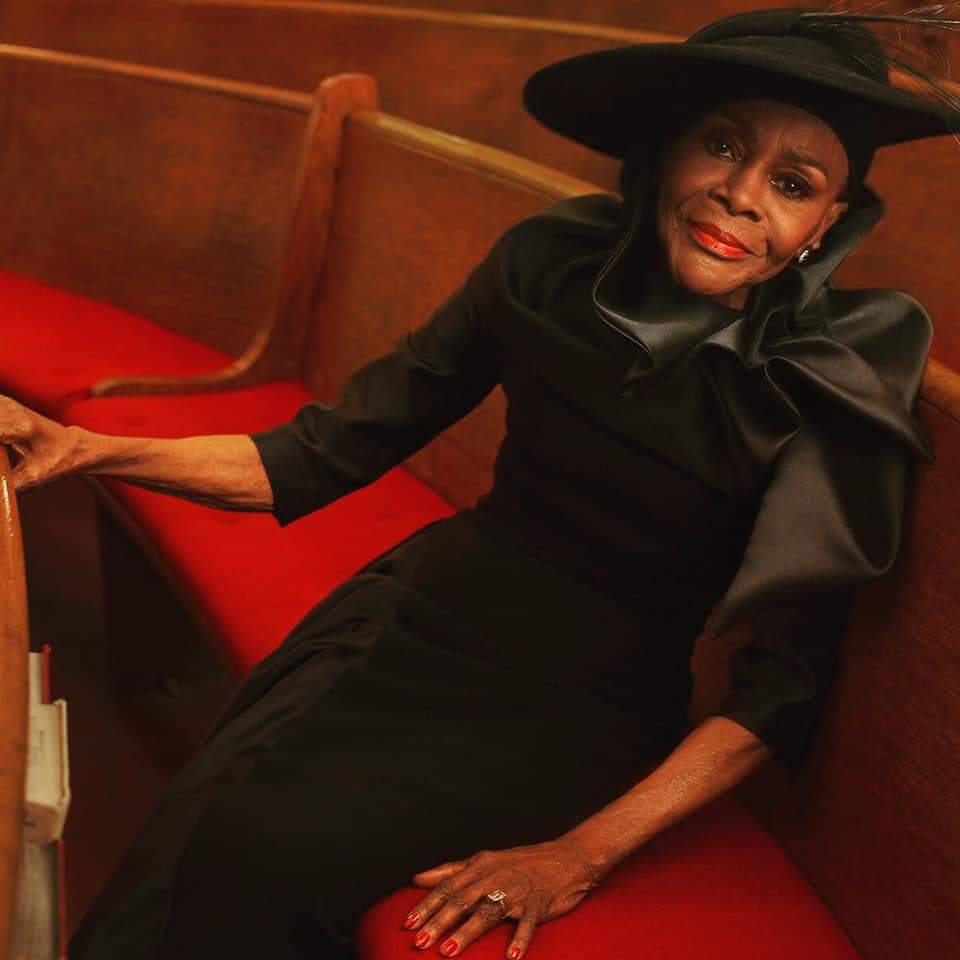 Elegant woman in church wearing black hat.