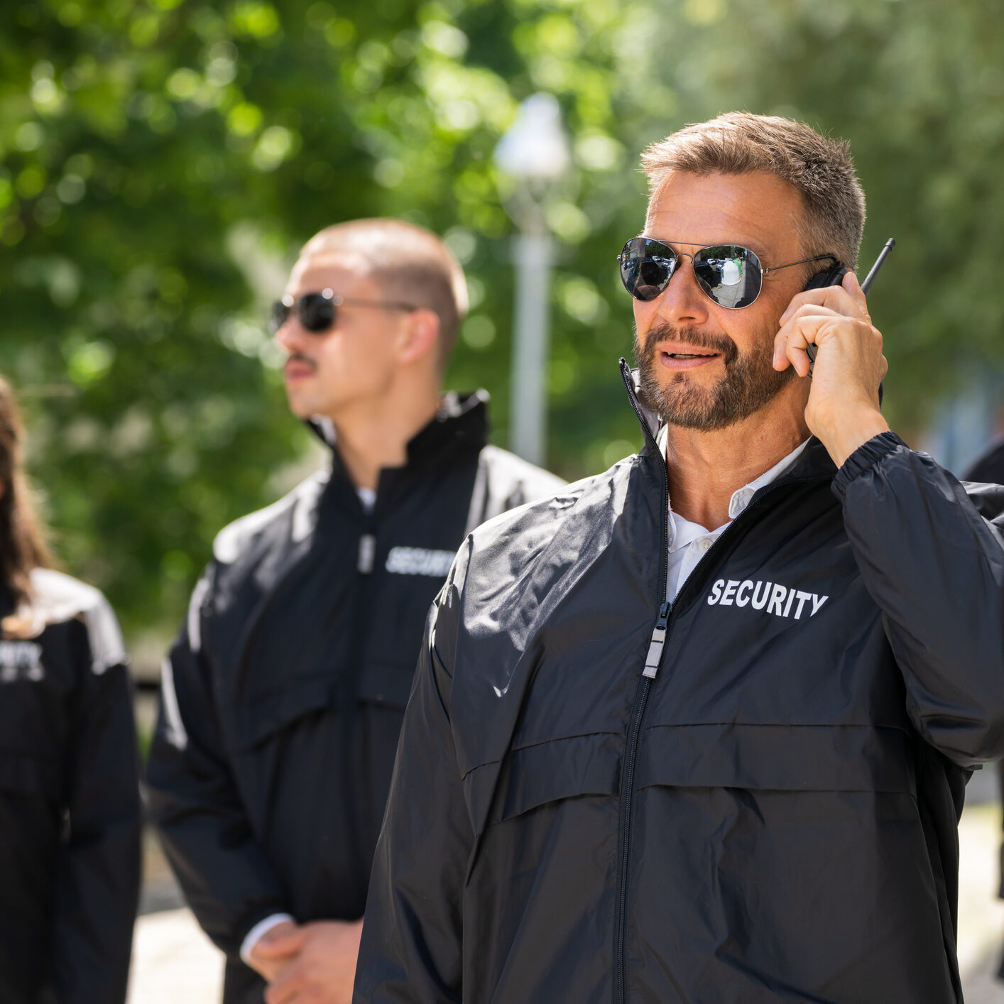 Security team wearing sunglasses and jackets outdoors.