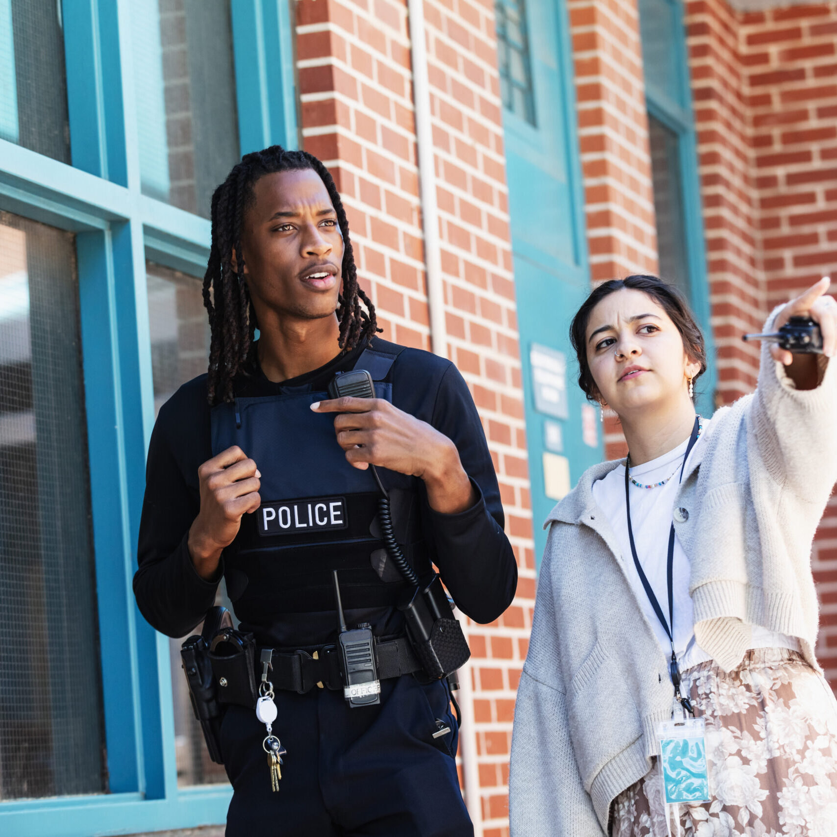Two people talking near brick building
