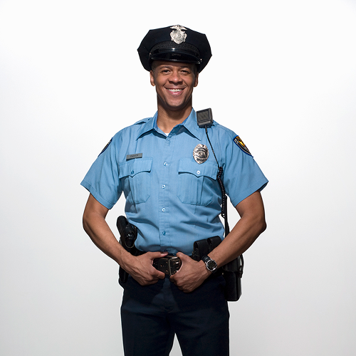 Smiling police officer in uniform, white background.